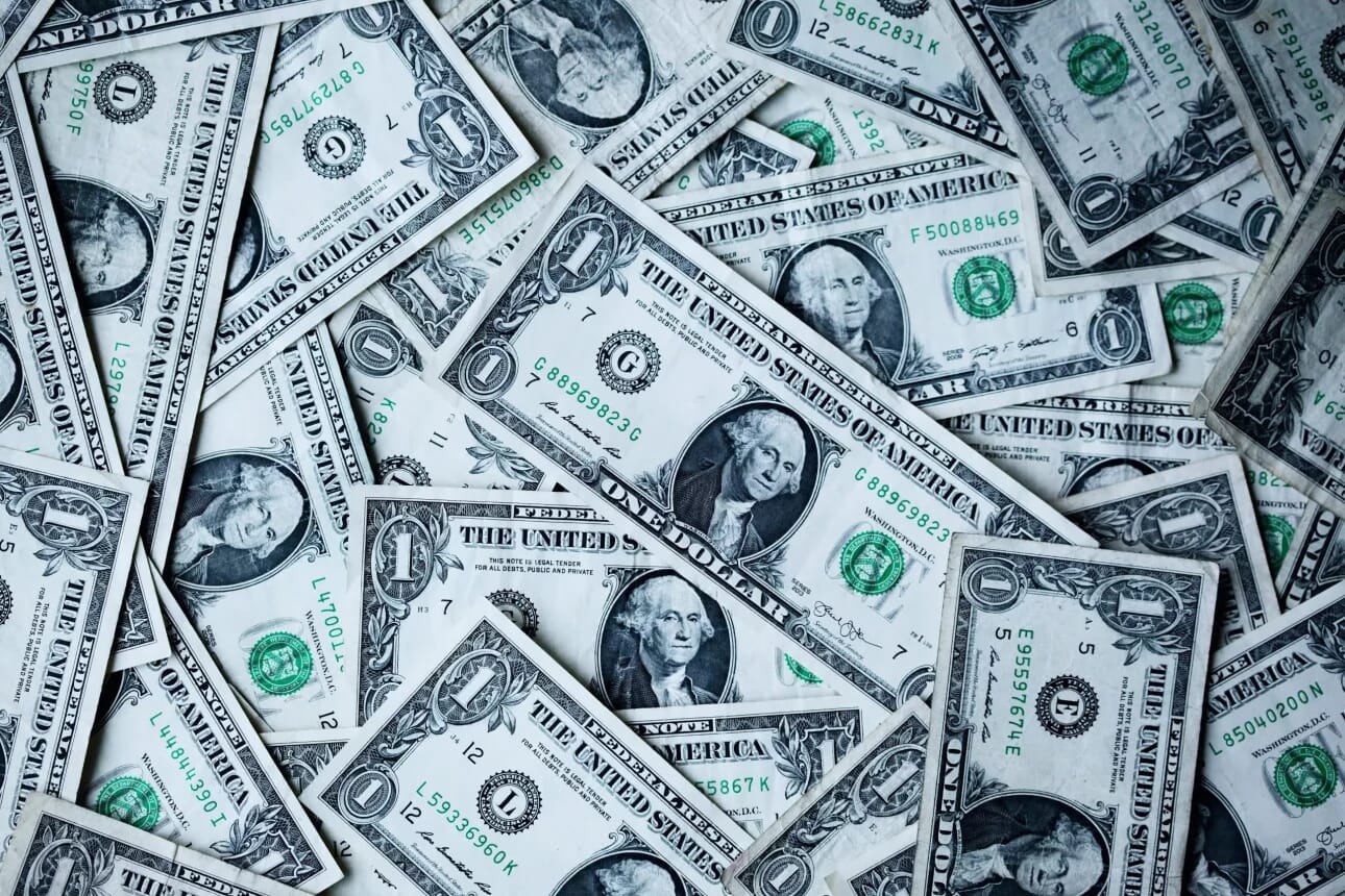 Ein Stapel US-Dollar-Scheine vor schwarzem Hintergrund.